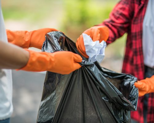 Men and women helped to collect garbage in a black bag.